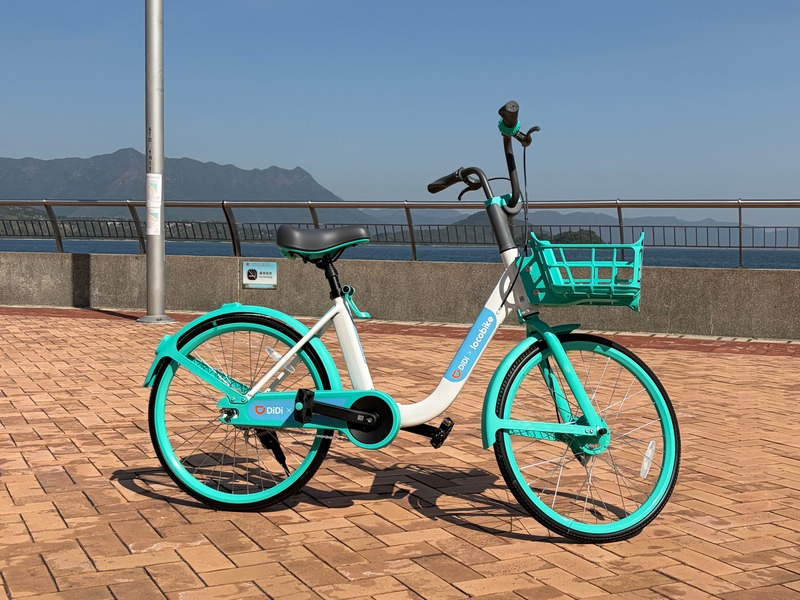 A teal LocoBike parked on a Hong Kong harbourfront promenade
